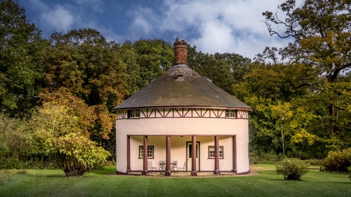 The exterior of The Round House, a rotunda cottage with a portico over a patio, Suffolk